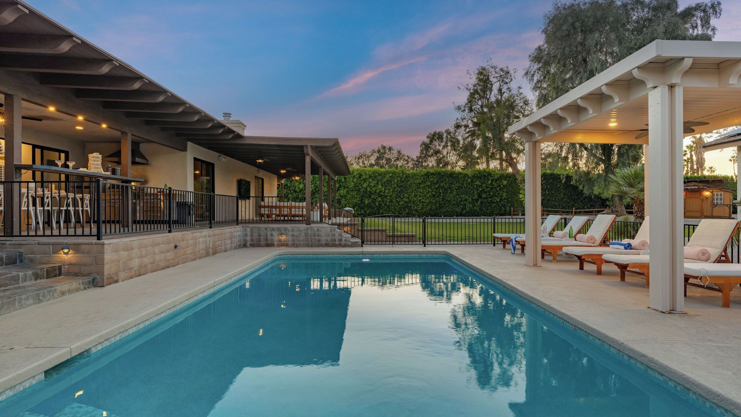 Een zwembad met ligbedden en een overdekt terras.