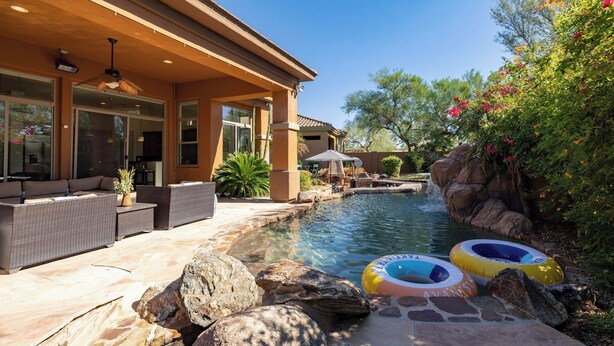 A pool area with a patio, lounge chairs, and inflatable rings.