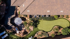 Eine Vogelperspektive eines Anwesens mit Schwimmbad, Golfplatz und einer Terrasse mit Gartenmöbeln.