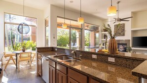 A modern kitchen with granite countertops, a stainless steel sink, and pendant lighting.