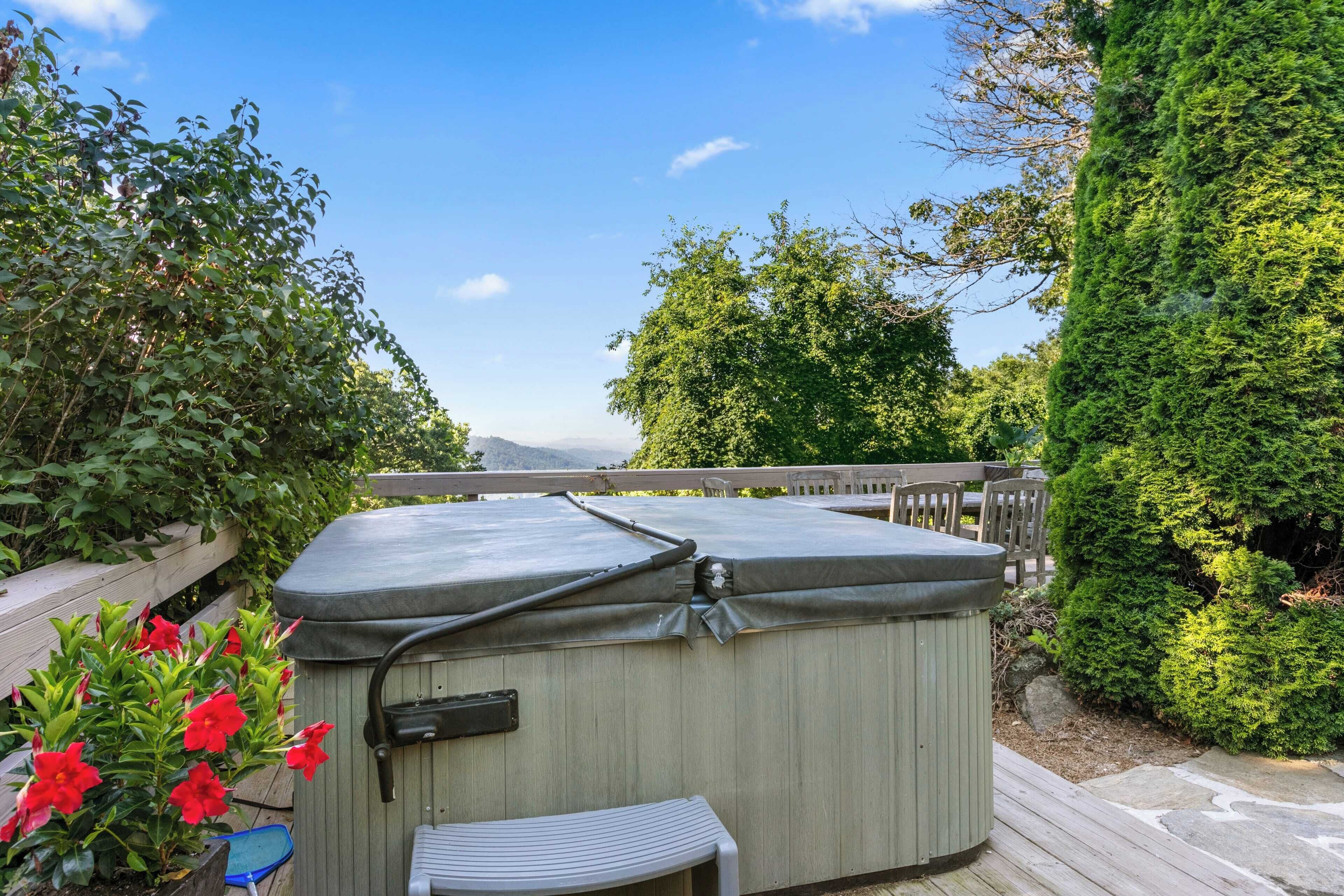 A hot tub on a wooden deck with a view of trees and mountains in the background.