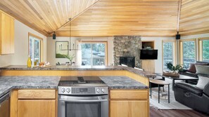 A modern kitchen with granite countertops, a built-in oven, and a stone fireplace. - Tanner by Avantstay Modern Cascades Escape (Bend)