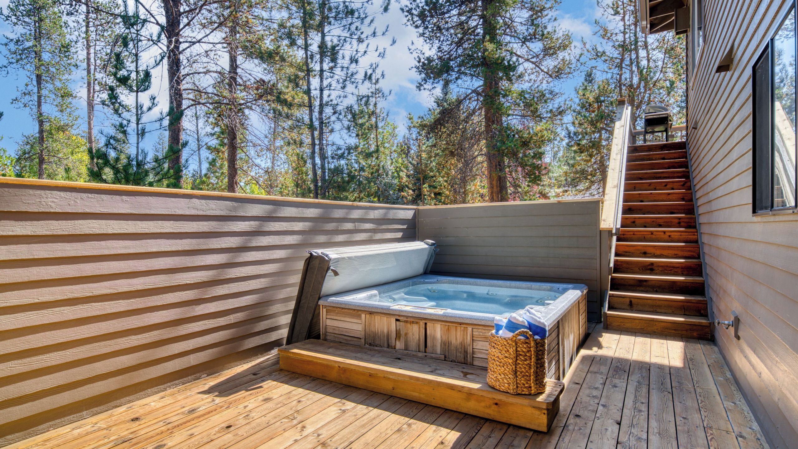 A hot tub on a wooden deck with a view of trees.