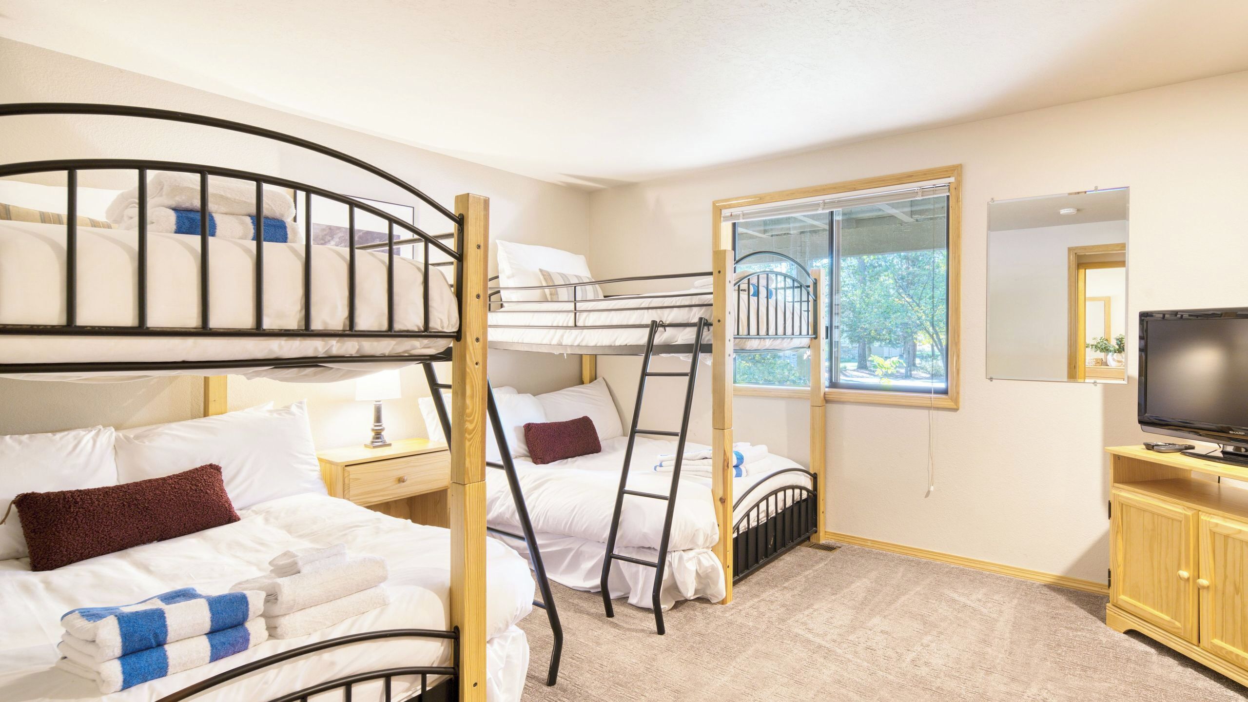A bunk bed room with a TV and a window.