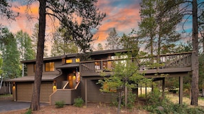 A two-story wooden cabin with a covered porch and a staircase leading to the upper level.