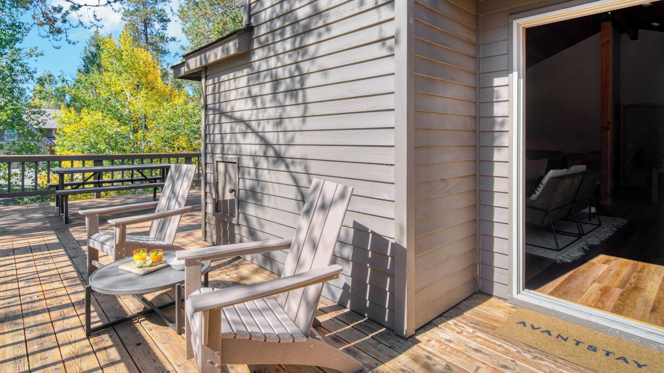 A wooden deck with outdoor seating and a door to a room.