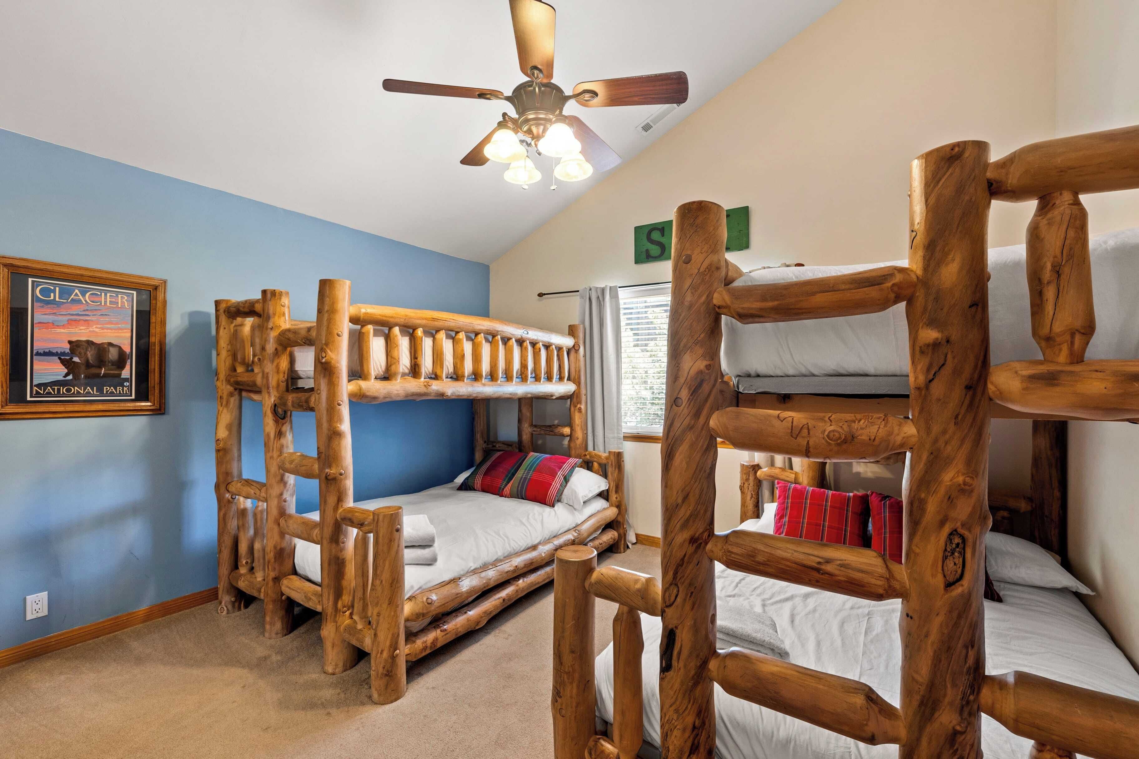 Ein Zimmer mit Holzbunkebetten, einem Deckenventilator und einem gerahmten Bild eines Gletschers.