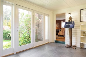 A hotel entrance with a sliding glass door, a wooden floor, a bench, and a blue bag labeled 'AVANTSTAY' on a stand. - Whitney by Avantstay Private Berkshires Estate (Sheffield)