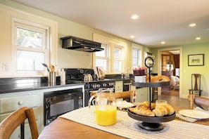 A kitchen with a stove, microwave, and a dining table with breakfast items. - Whitney by Avantstay Private Berkshires Estate (Sheffield)