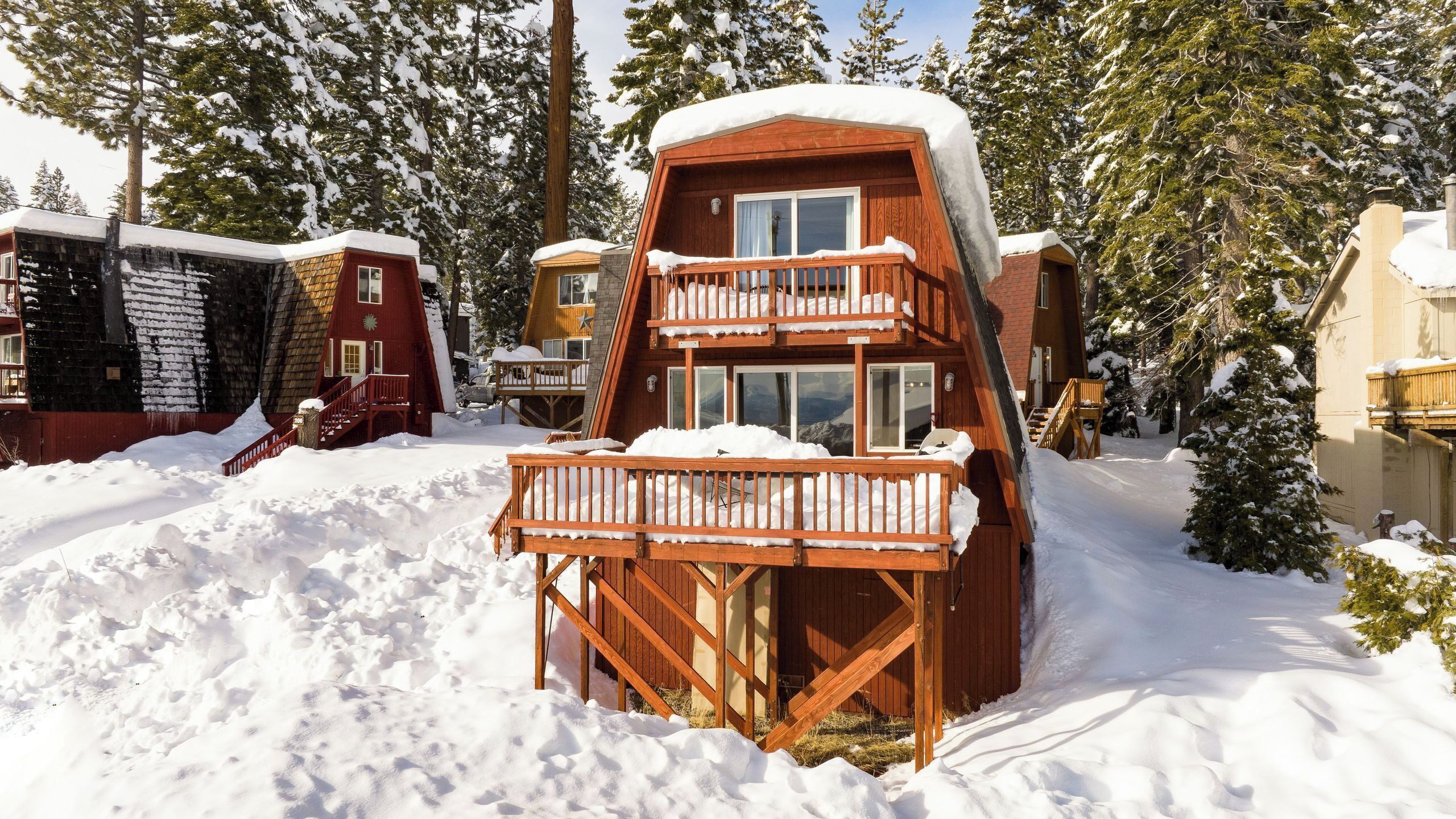 A wooden cabin with a balcony, surrounded by snow-covered trees.