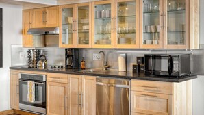 A modern kitchen with wooden cabinets, stainless steel appliances, and glass-fronted upper cabinets.