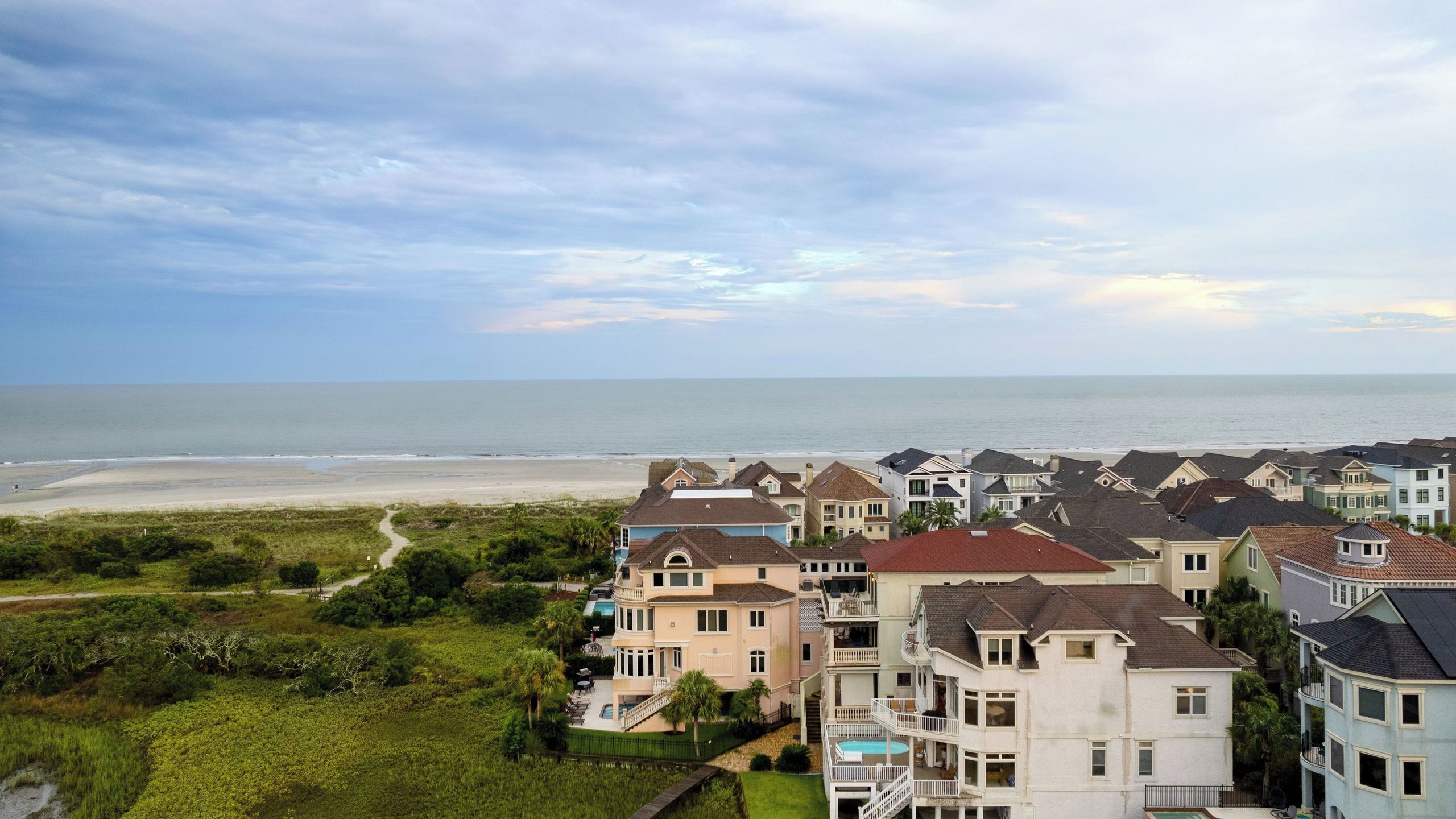 A coastal residential area with houses, a beach, and a clear sky.
