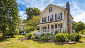 A two-story house with a front porch, a brick chimney, and a well-maintained garden. - Cordelia by Avantstay Amazing Backyard, 10mins From Stockbridge! (Lee)