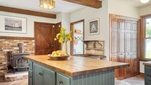 A kitchen with a wooden island, a brick wall, a vintage stove, and a large wooden door. - Cordelia by Avantstay Amazing Backyard, 10mins From Stockbridge! (Lee)
