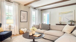 A cozy living room with a sofa, a coffee table, a lamp, and a framed botanical print on the wall. - Cordelia by Avantstay Amazing Backyard, 10mins From Stockbridge! (Lee)