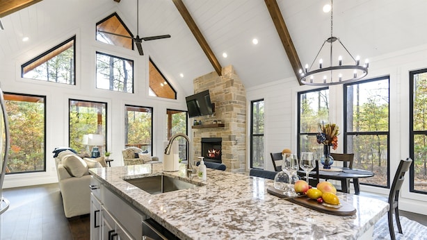 Cocina amplia con una isla grande, chimenea de piedra y ventanas grandes que ofrecen vistas al exterior.