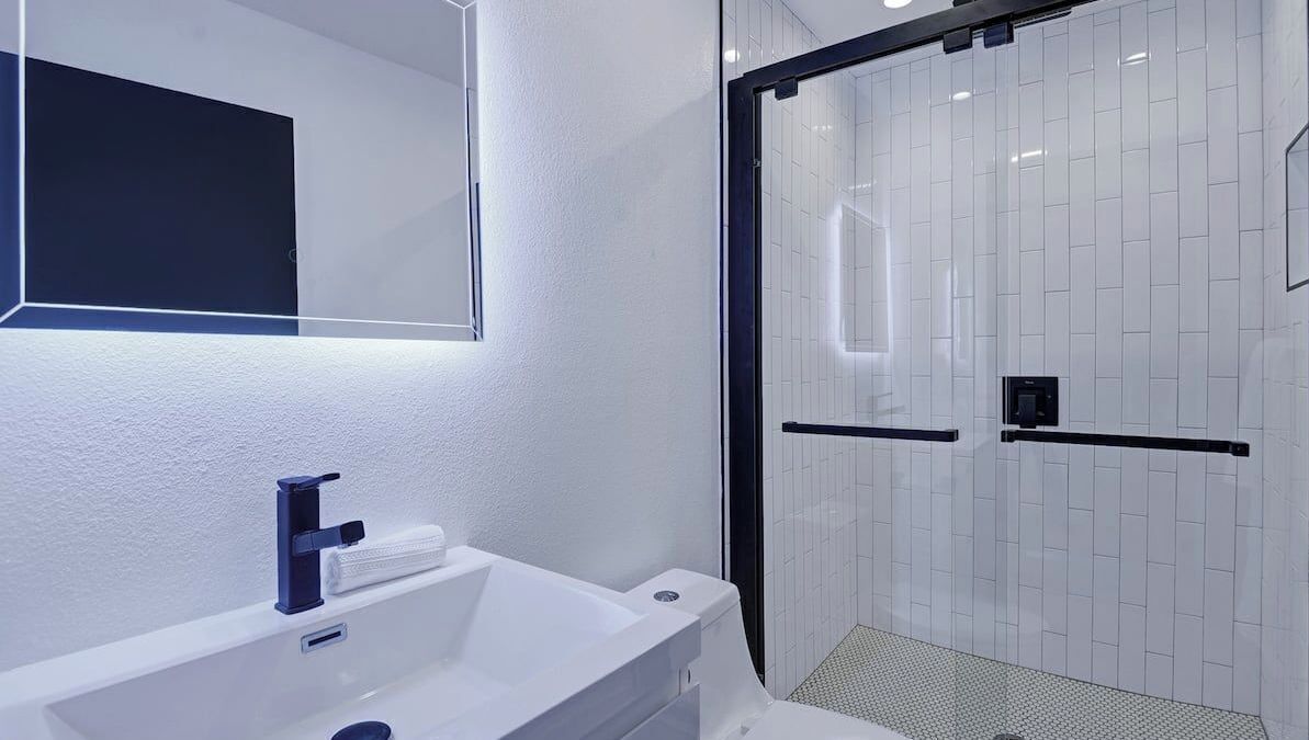 A modern bathroom with a white sink, a mirror, and a glass-enclosed shower area.