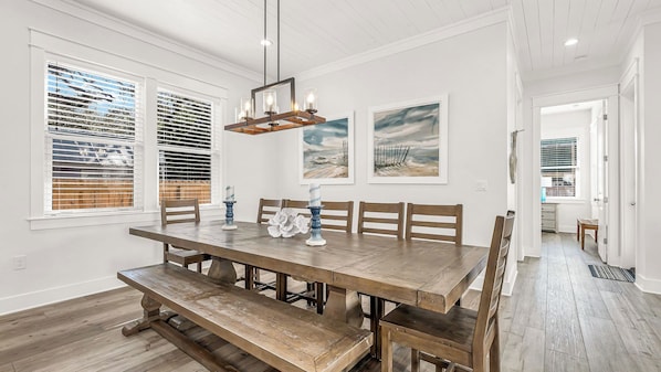 Une salle à manger avec une table en bois, des bancs et un lustre.