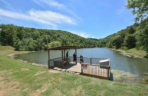 A wooden pier with a covered seating area overlooking a lake, surrounded by lush greenery. - Mountain Getaway - So Close to SDC -2 Outdoor Pools - Hiking (Branson West)