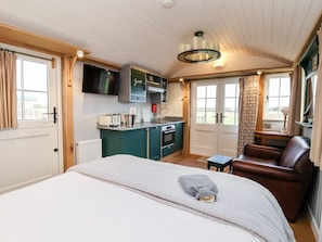 A compact room with a bed, a small table, a chair, a kitchenette, and a TV mounted on the wall. - Amy Johnson (York)