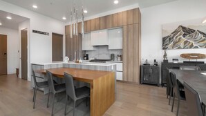 A modern kitchen with a central island, wooden cabinets, and a dining area with chairs. - Slopewatch by Avantstay Ski-in/out Luxe Retreat (Park City)