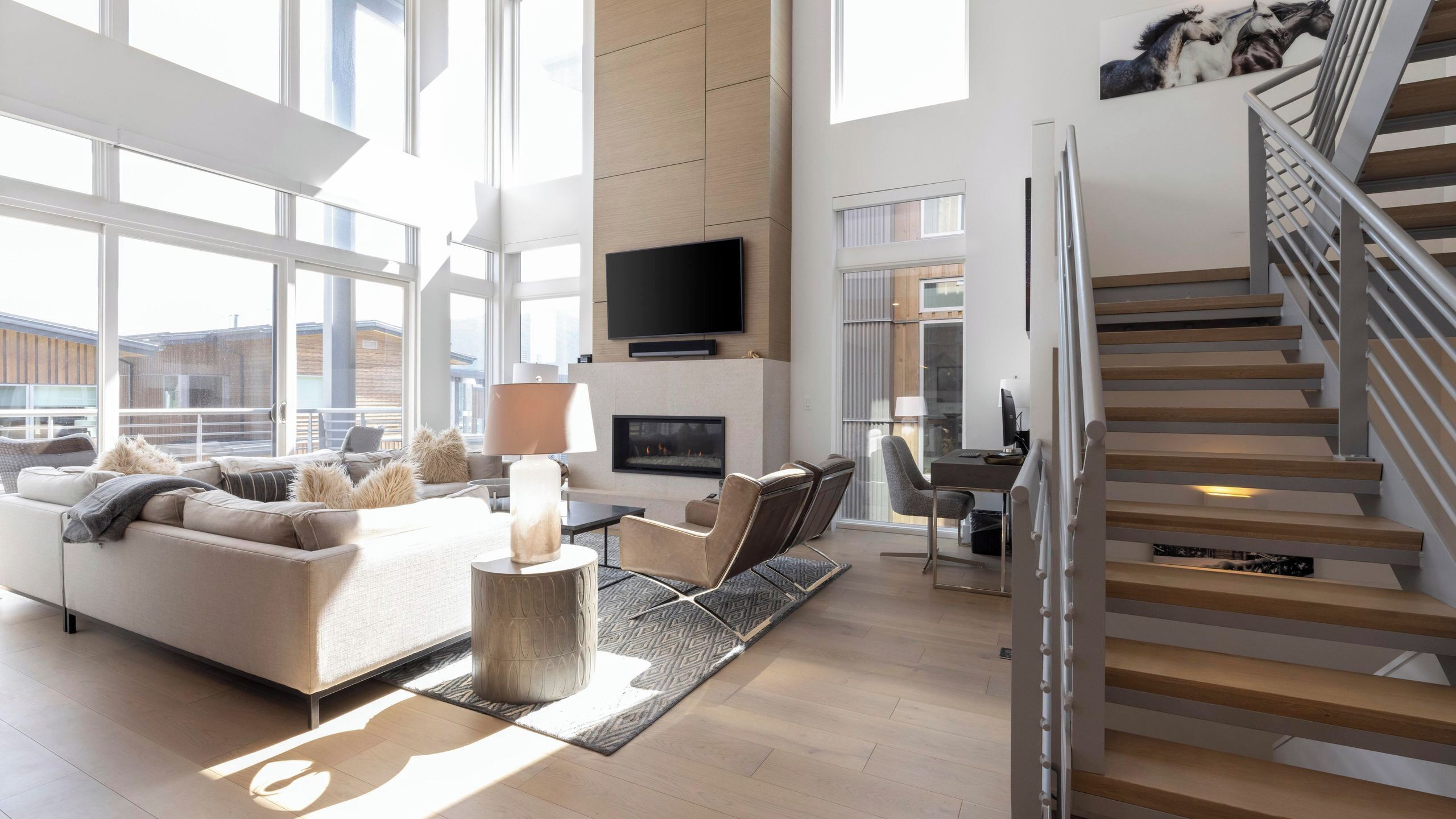 Ein großzügiger Wohnbereich mit Sofa, Kamin, Fernseher und einer Treppe.