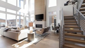 A spacious living area with a sofa, a fireplace, a TV, and a staircase. - Slopewatch by Avantstay Ski-in/out Luxe Retreat (Park City)