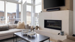 Un salon moderne avec une cheminée, un canapé, une table basse et de grandes fenêtres.