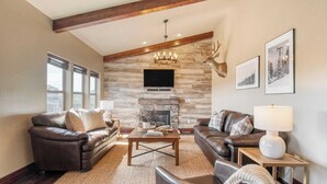 A living room with leather sofas, a stone fireplace, a mounted deer head, and framed pictures on the wall. - Lucky Bill by Avantstay Lake Views, 15mins to Park City Mtn (Heber City)