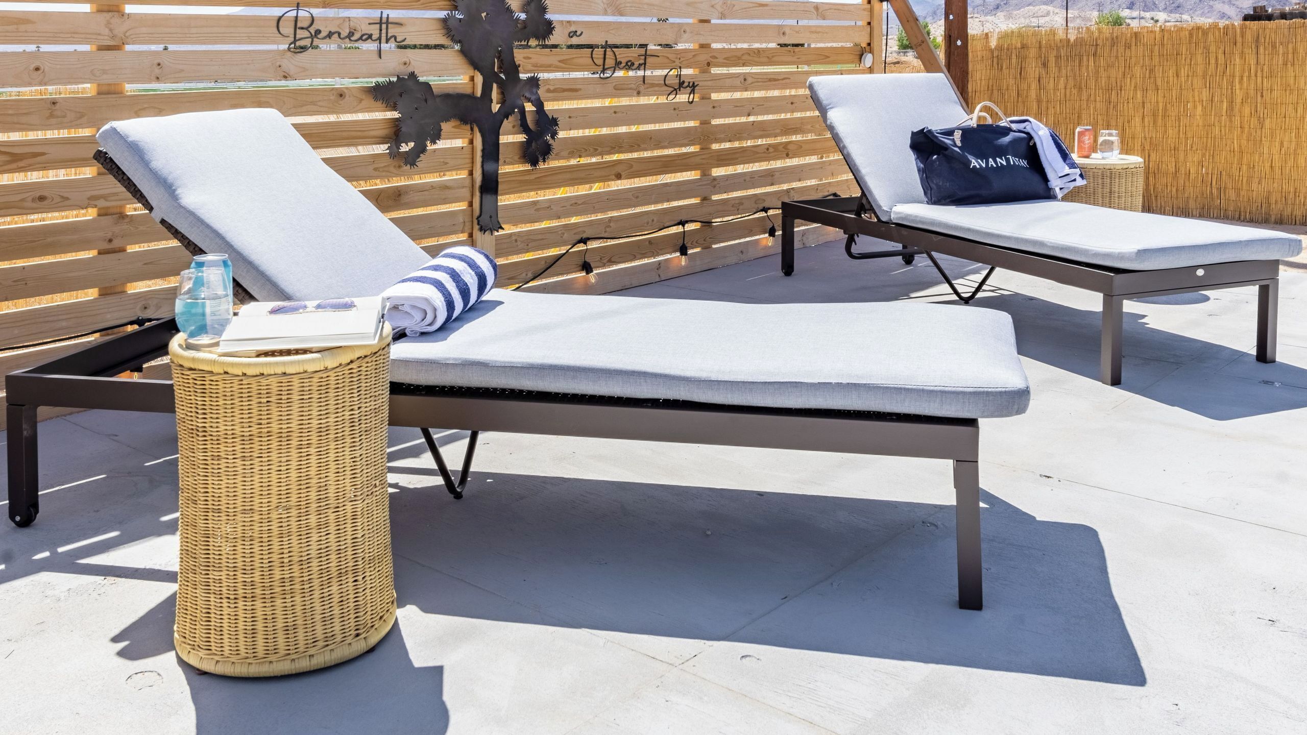 Two lounge chairs with cushions, a wicker basket, and a decorative metal tree.