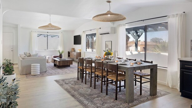 A spacious living area with a dining table, chairs, and a sofa.