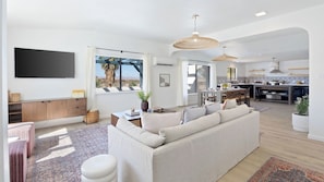 A modern living room with a sofa, TV, and large windows.