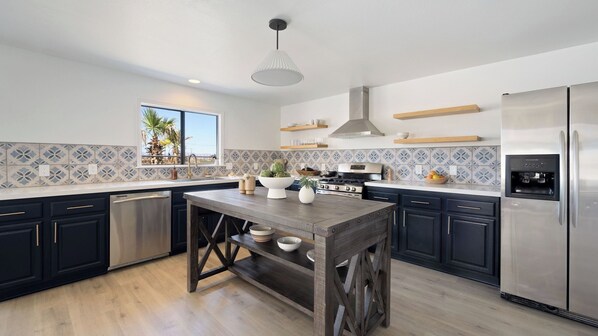 A modern kitchen with a central island, stainless steel appliances, and a water dispenser.