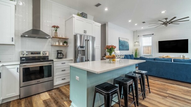 A modern kitchen with white cabinets, stainless steel appliances, and a central island with stools.