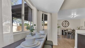 Et moderne køkken med spiseplads, store vinduer og et ur på væggen.