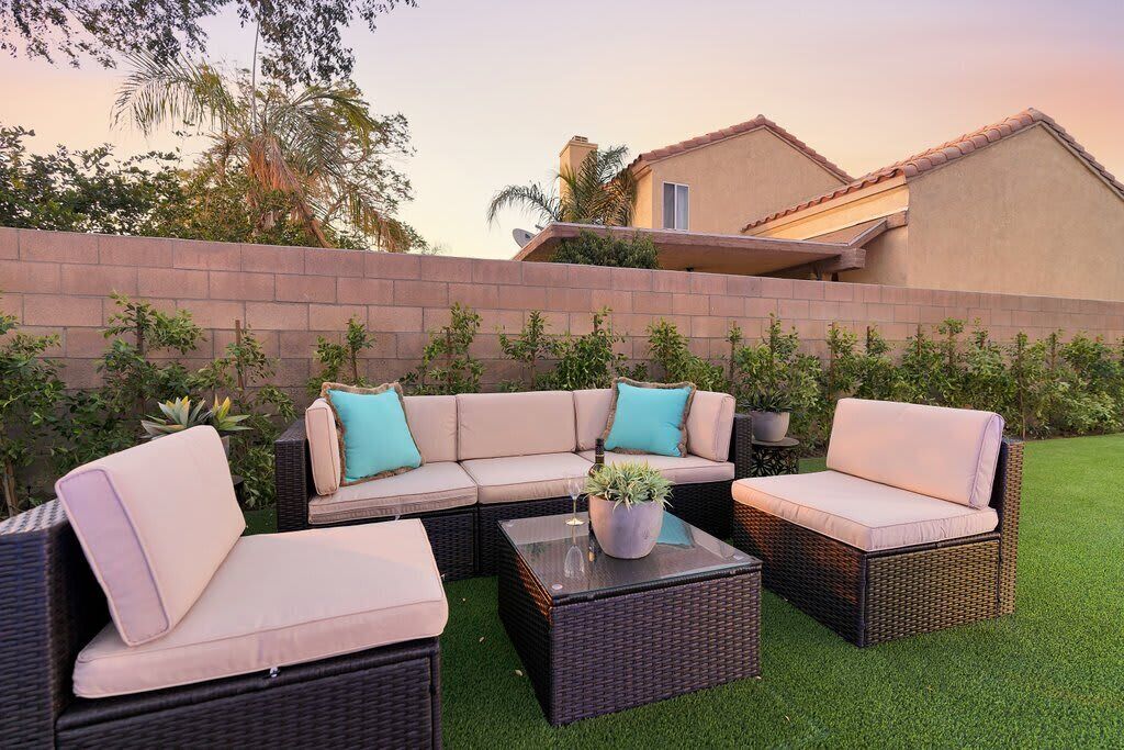 A patio with wicker furniture, a glass coffee table, and a potted plant.
