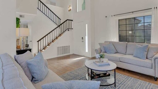 En moderne stue med trappe, sofa, sofabord og et stort vindue.