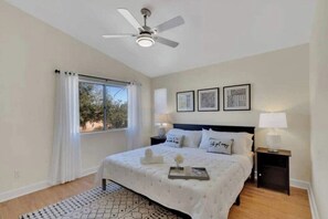 A bedroom with a bed, a ceiling fan, a window with curtains, bedside tables, and framed pictures on the wall. - Casa Nueva: 4 bedroom Pool, Spa, Games, close to Polo (Indio)