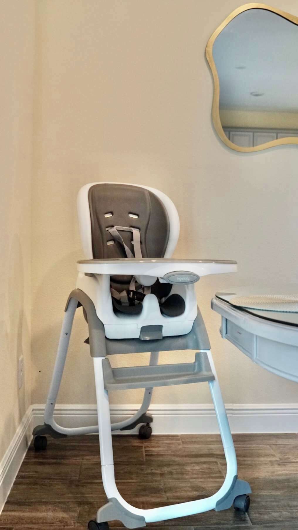 A high chair with a tray table and a foldable seat.