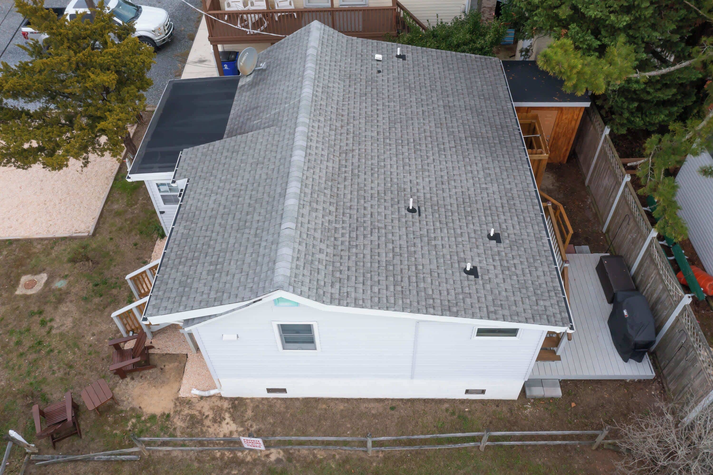 A residential house with a sloped roof, a fenced backyard, and a satellite dish.
