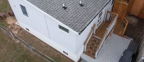 Una casa de un piso con techo de tejas grises, una terraza de madera y un pequeño porche.