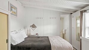 A bedroom with a bed, a nightstand, a lamp, and a coat rack. - Cozy Gem (Dewey Beach)