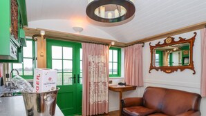 Una sala de estar acogedora con una puerta verde, un sofá de cuero, una pequeña mesa de madera y un taburete rojo.