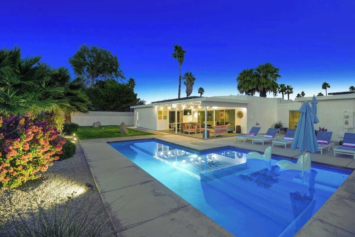Ein modernes Haus mit Swimmingpool, Liegestühlen und einer Terrassenfläche.