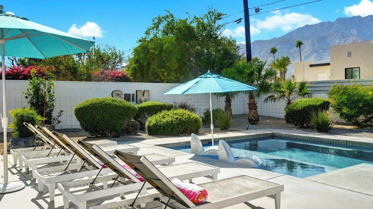 A pool area with lounge chairs, umbrellas, and well-maintained landscaping.