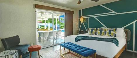 A modern hotel room with a bed, a bench, a chair, and a ceiling fan.