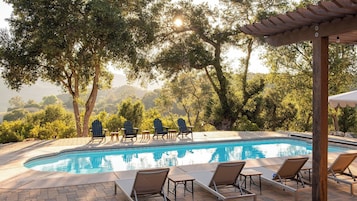 Uma área de piscina com espreguiçadeiras e um pérgola.