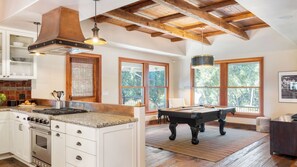 A spacious kitchen with a central island, a dining area with a pool table, and large windows offering views of the outdoors. - Dolcetto by Avantstay Wine Country Mansion, Minutes From Vineyards (Paso Robles)