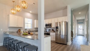 A modern kitchen with white cabinets, stainless steel appliances, and a central island with bar stools. - Tidepool by Avantstay 2min Walk to Miramar Beach! (Miramar Beach)