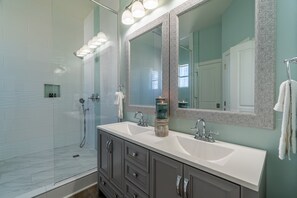 A modern bathroom with a glass shower enclosure, a double sink vanity, and a large mirror. - Tidepool by Avantstay 2min Walk to Miramar Beach! (Miramar Beach)